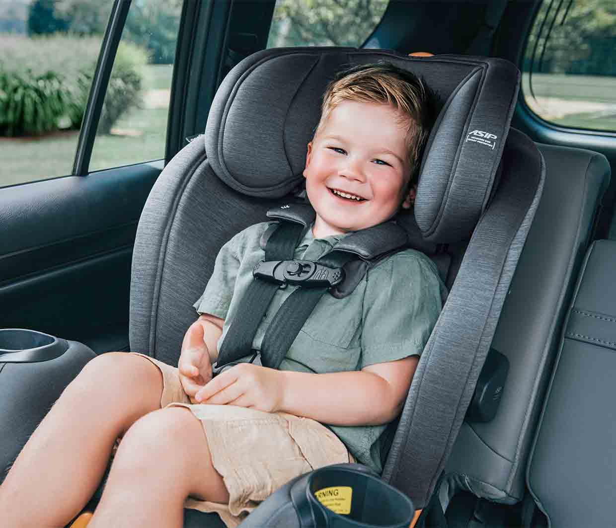 Smiling toddler sitting forward-facing in a Chicco OneFit LX ClearTex car seat inside a vehicle.