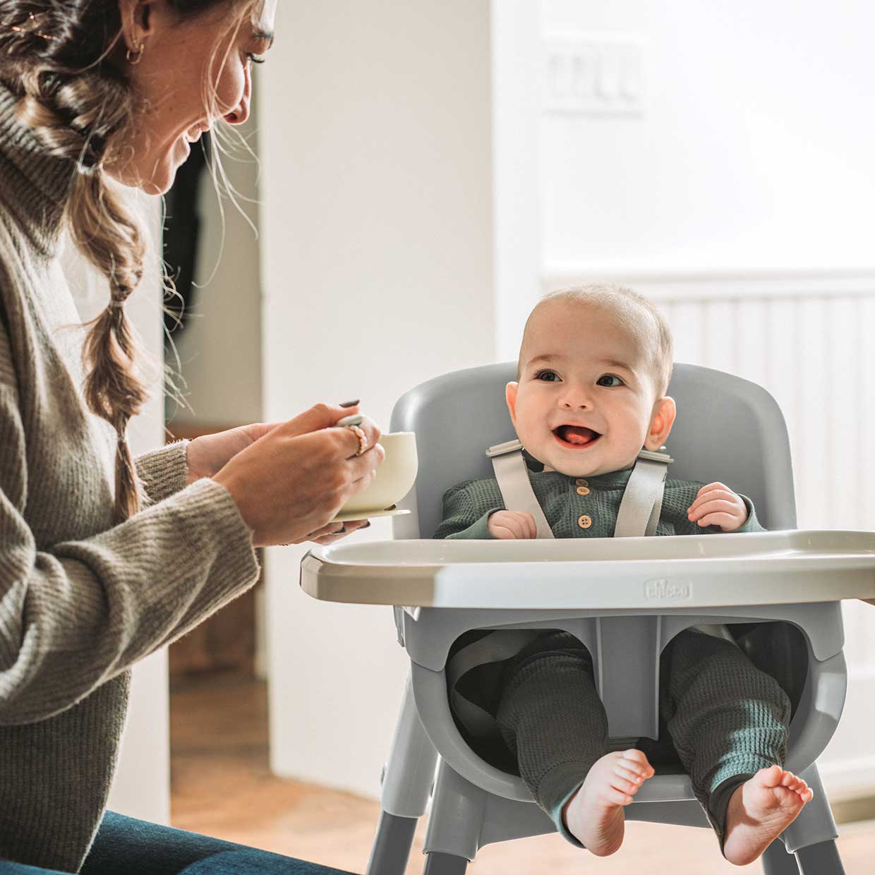 Mother feeding a baby sitting in a Chicco Zest 4-in-1 Folding High Chair