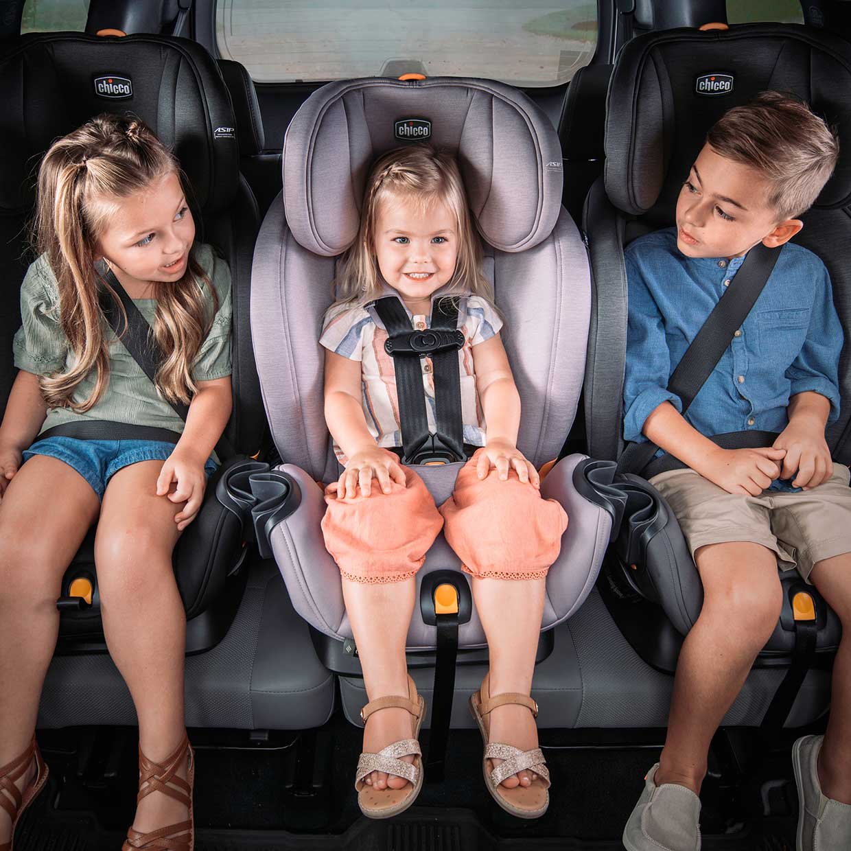 Three Chicco OneFit LX car seats across with children image
