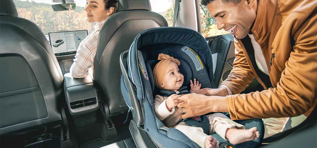 A father checks on his child’s rear-facing car seat installation
