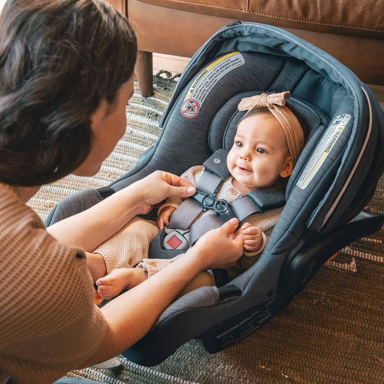 Baby being buckled in to the Chicco KeyFit Max Zip ClearLux Infant Car Seat