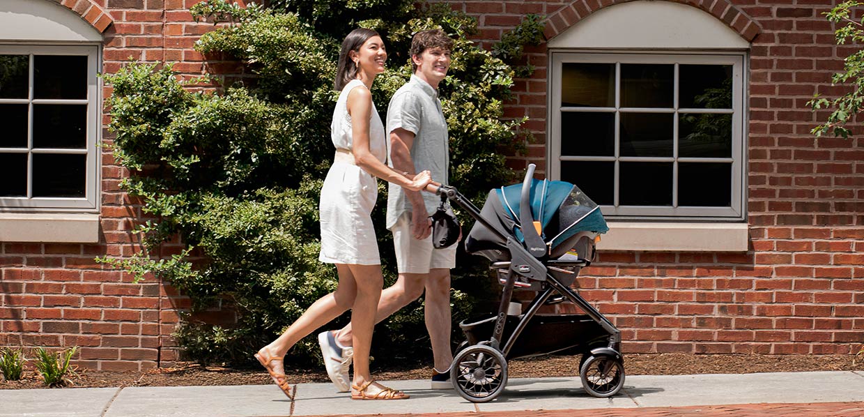 Parents pushing a Chicco Corso Primo Travel System with stroller and car seat