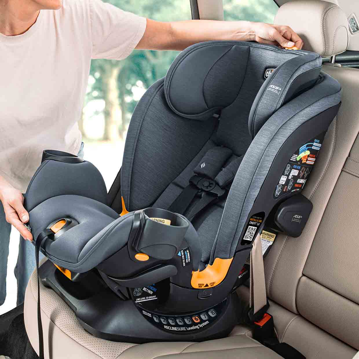 Caregiver adjusting the recline angle on a Chicco OneFit LX All-in-One Car Seat image